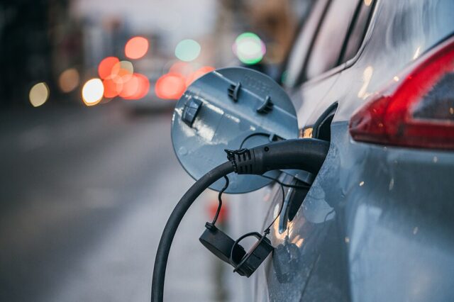 Close-up_of_an_electric_car_charging._Traffic_lights_in_a_blurry_background